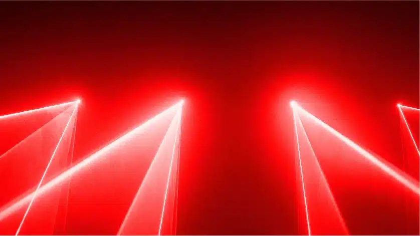 Red laser light beams in a dark room.