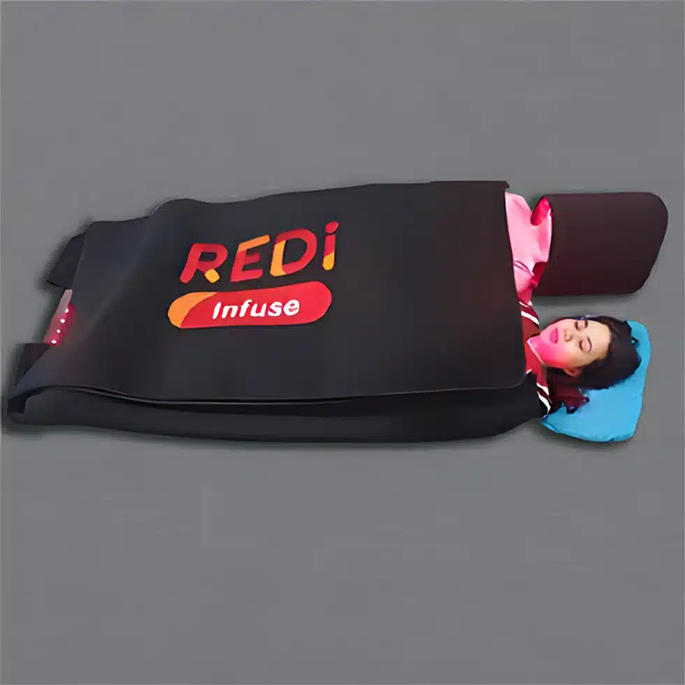 A woman is laying on a bed undergoing REDi Infuse Plus fitness bag immersion therapy.