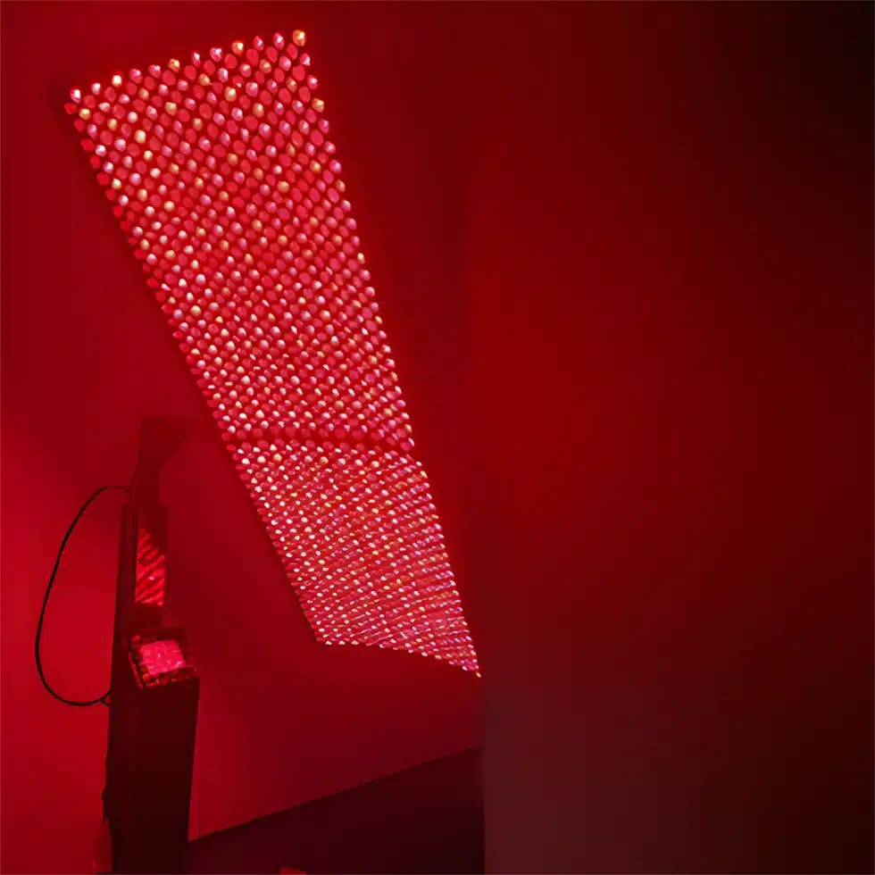 A professional red light therapy panel in a dark room.
